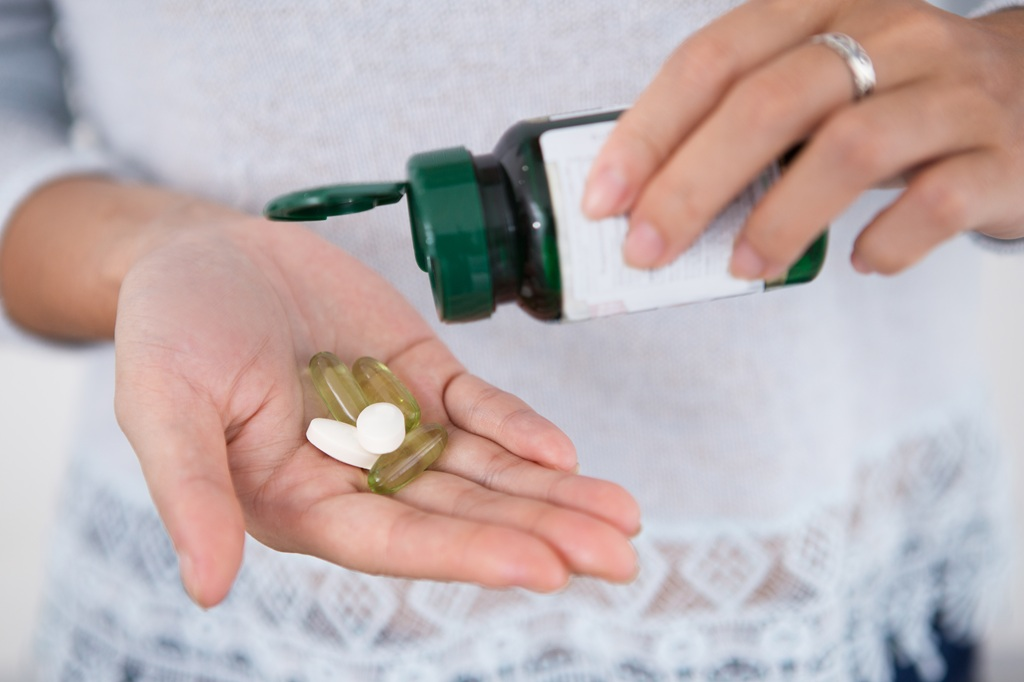 Older woman taking her customized supplements.  supplements for people 60 and older